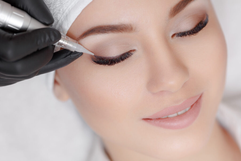cosmetologist making permanent make up at beauty salon